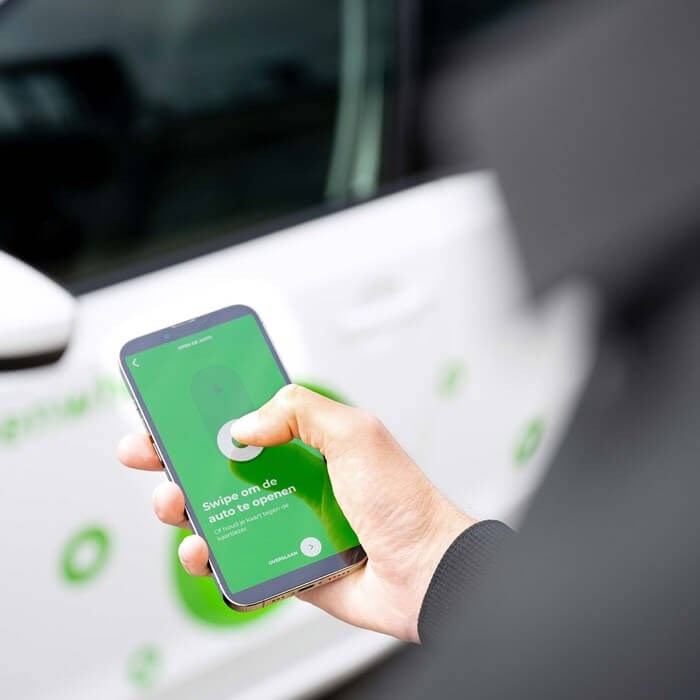 Persoon gebruikt app om elektrische deelauto te openen