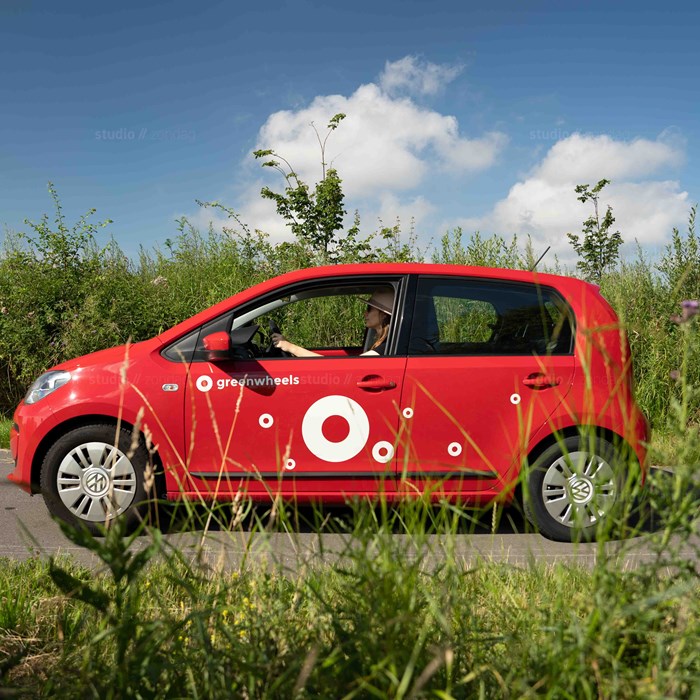 Volkswagen up! Greenwheels in natuurgebied met vrouw achter stuur