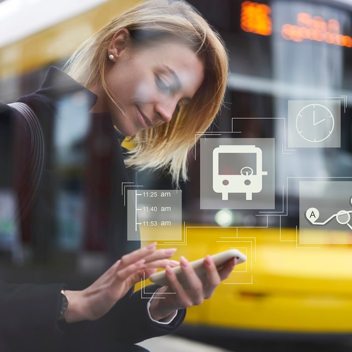 Vrouw gebruikt mobiele telefoon om zakelijke reis te plannen met tram op achtergrond