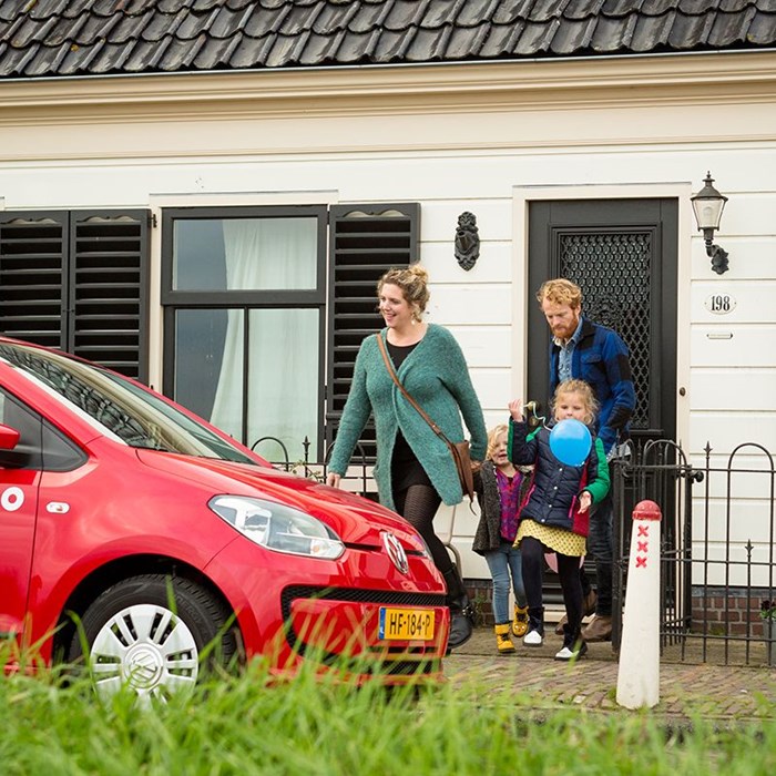 Gezin met kinderen gaat dagje weg met rode Greenwheels deelauto