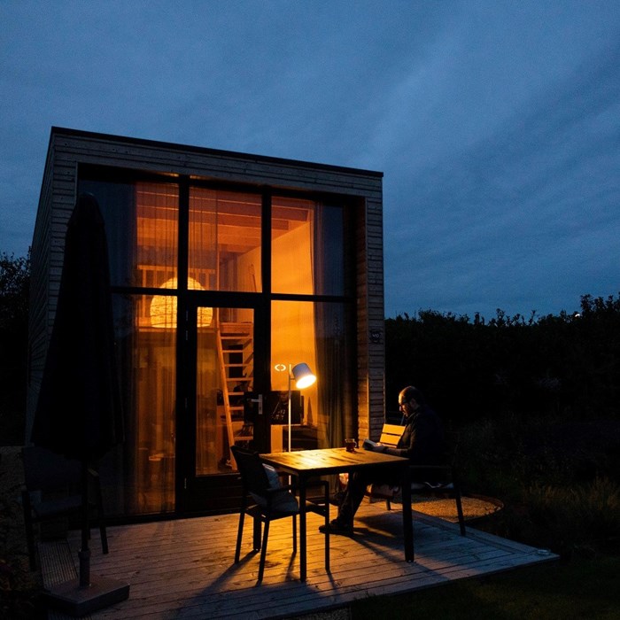 Man buiten bij Tiny House in de avond in de natuur