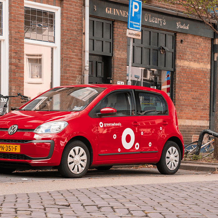 Greenwheels deelauto Utrecht nabij restaurant fietser komt langs