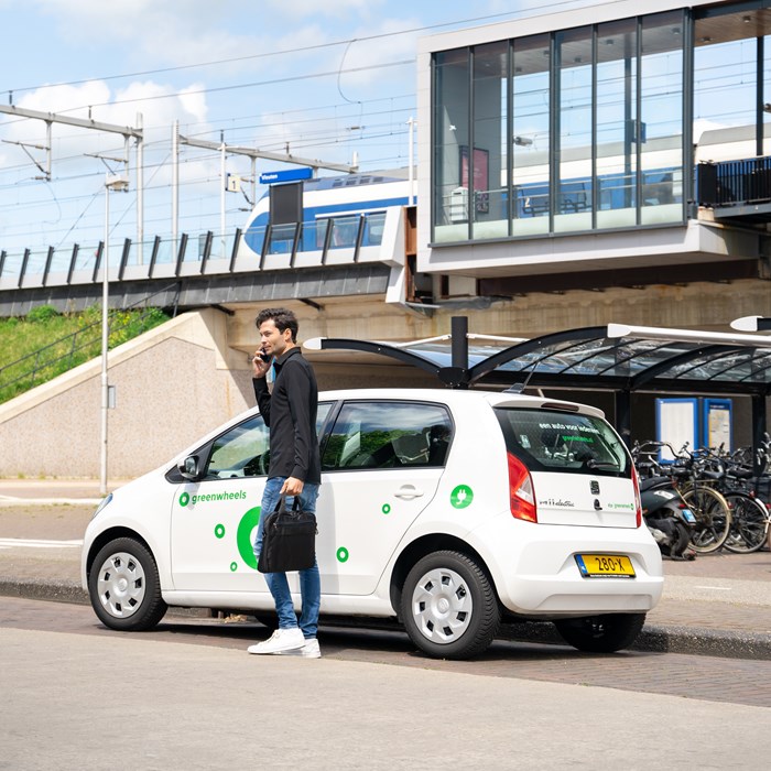 Man belt bij elektrische Greenwheels auto bij NS-station