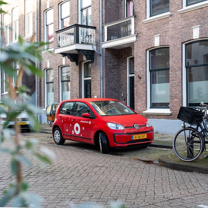 Greenwheels deelauto op straat geparkeerd bij fiets in woonwijk