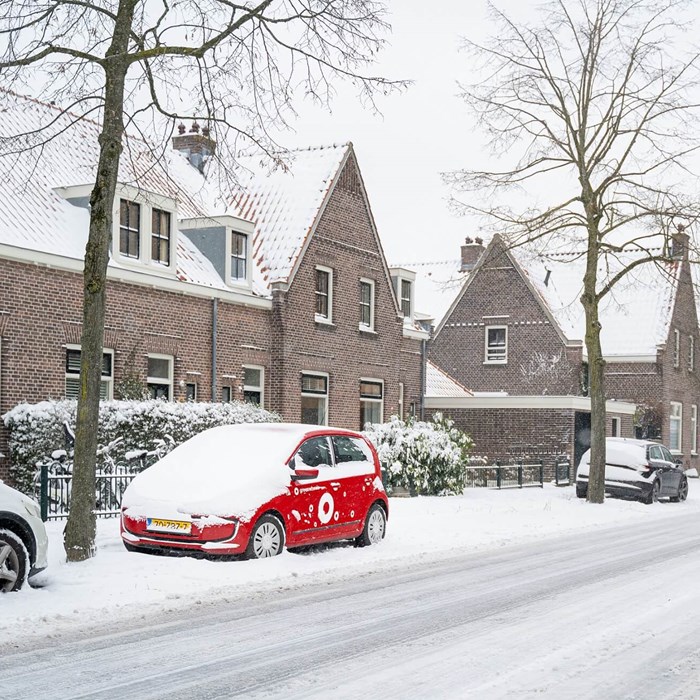 Greenwheels in sneeuw geparkeerd langs huizen