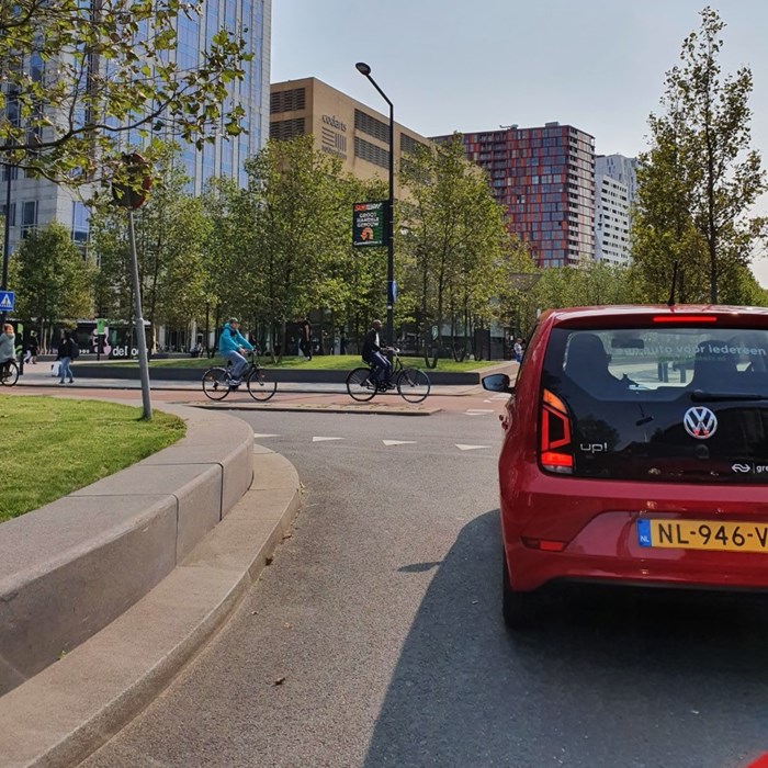 Greenwheels auto huren Rotterdam Centraal Station rijdend met fietser