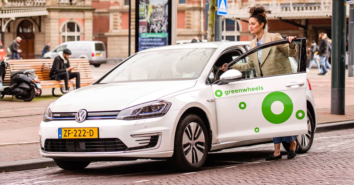 Dame stapt in Greenwheels e-Golf Elektrische auto bij Den Haag HS NS station