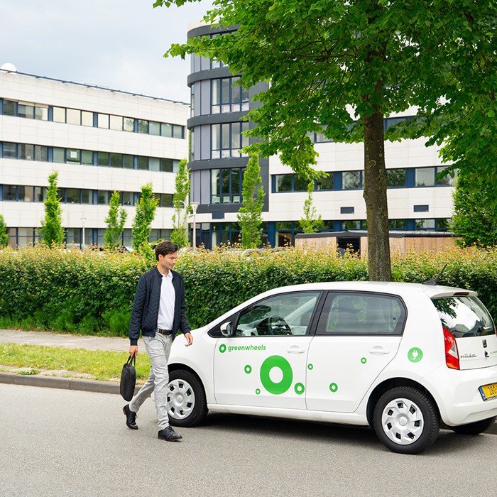 Man loopt naar elektrische deelauto van Greenwheels
