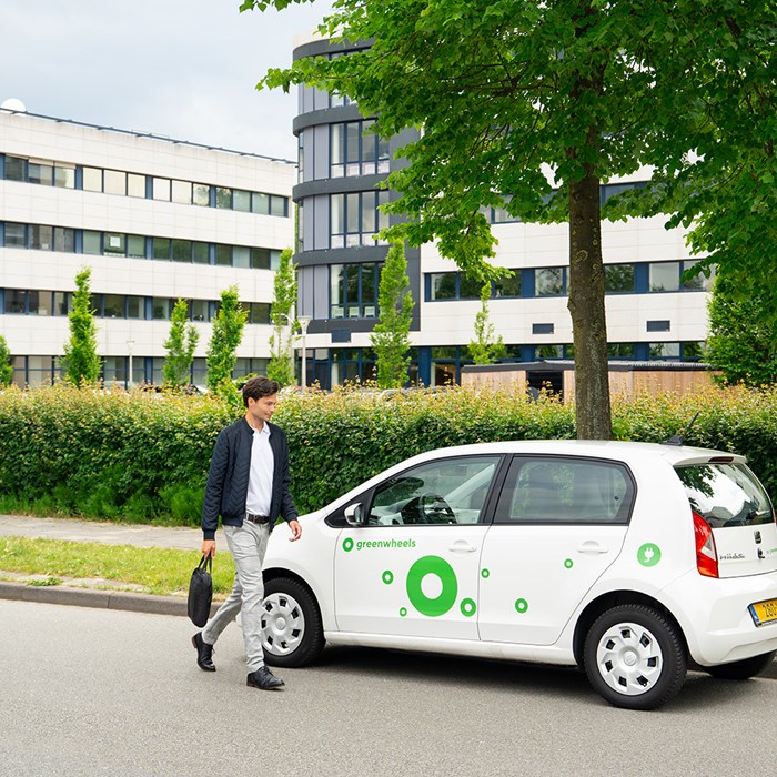 Man loopt naar elektrische deelauto van Greenwheels