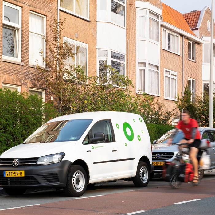 Greenwheels witte Caddy op straat Utrecht fietser auto huren